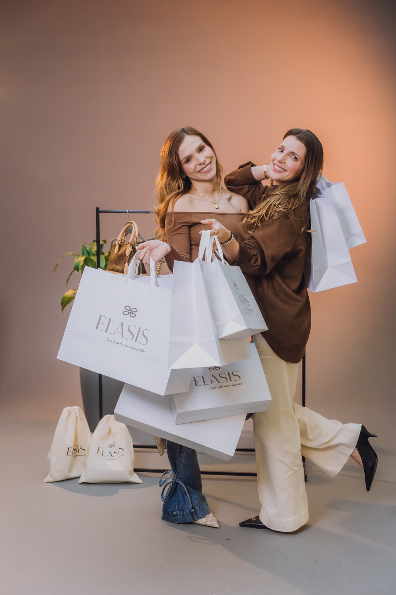 Cintia e Hannah, fundadoras da Elasis, cercadas por sacolas da marca